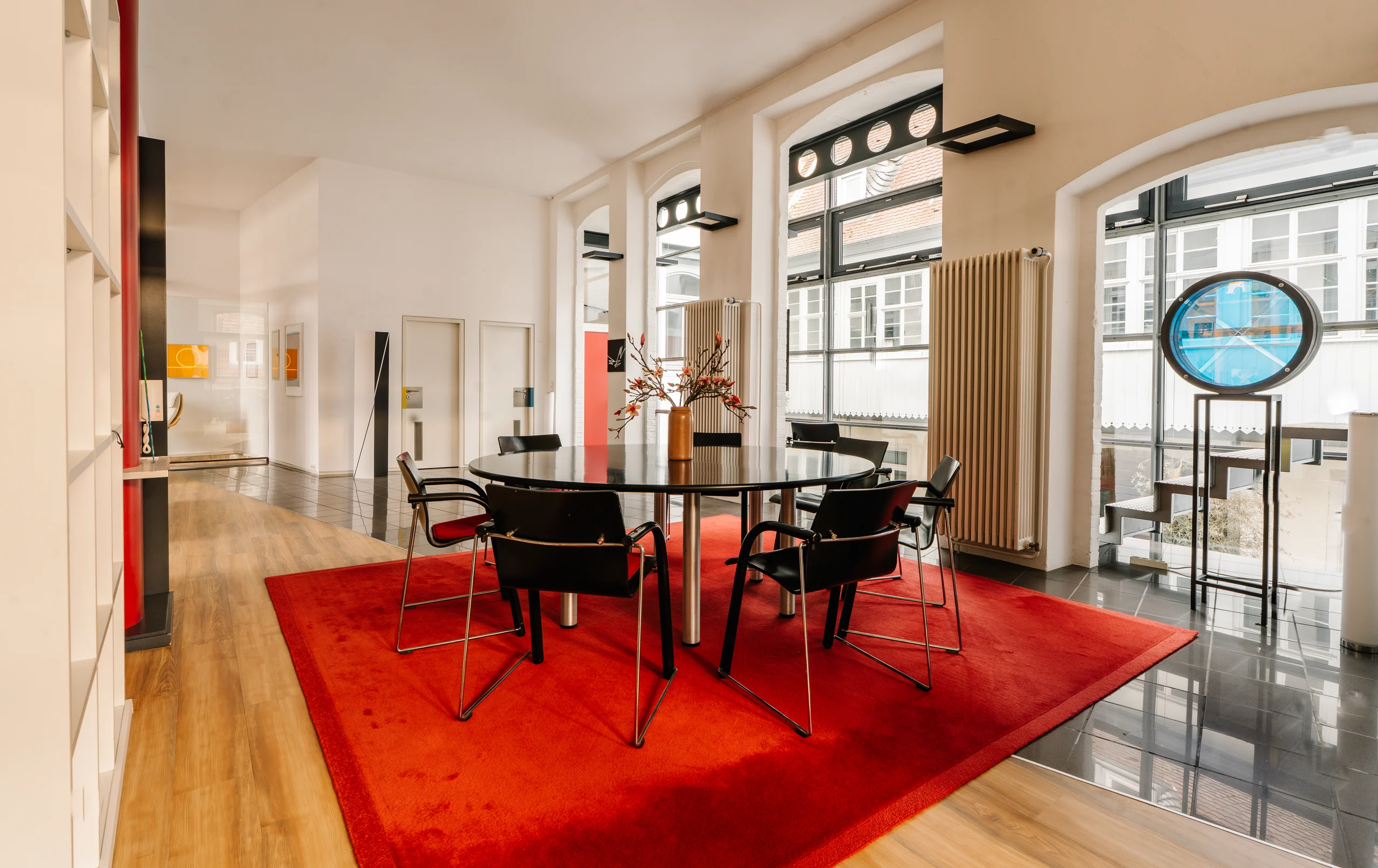 Essbereich im Loft mit rotem Teppich und hohen Sprossenfenstern